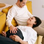 Man In White Long Sleeve Shirt Sitting On Yellow Couch With Pregnant Woman 7991995 150x150
