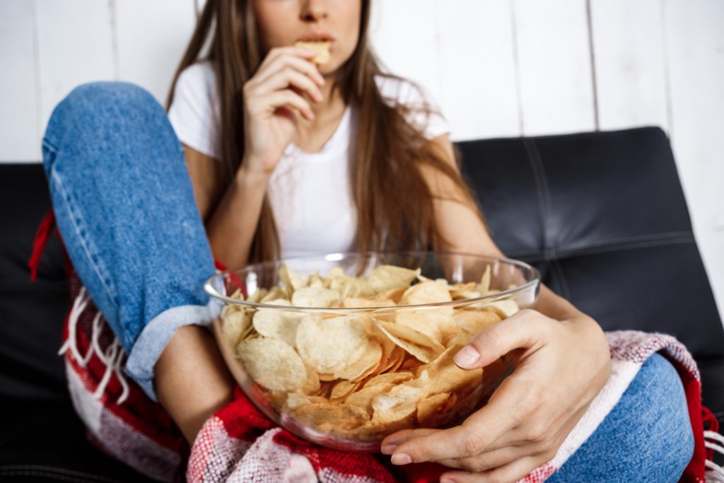 young pretty girl watching tv, sitting on sofa at home.